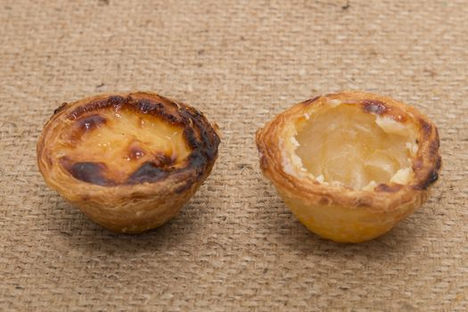 Famous Portuguese egg pastry tart called 'Pastel de Belem' on hessian fabric.