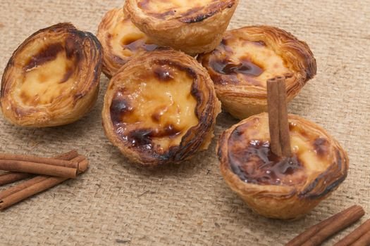 Famous Portuguese egg pastry tart called 'Pastel de Belem' on hessian fabric.