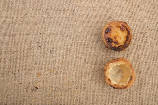 Famous Portuguese egg pastry tart called 'Pastel de Belem' on hessian fabric.