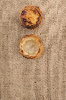 Famous Portuguese egg pastry tart called 'Pastel de Belem' on hessian fabric.