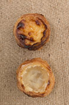 Famous Portuguese egg pastry tart called 'Pastel de Belem' on hessian fabric.