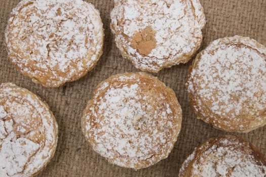 Famous Portuguese flaky Bean pastry sprinkled with white sugar powder on hessian fabric.