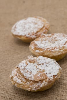 Famous Portuguese flaky Bean pastry sprinkled with white sugar powder on hessian fabric.