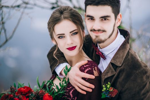 groom in a brown and bride in burgundy in the mountains Carpathians