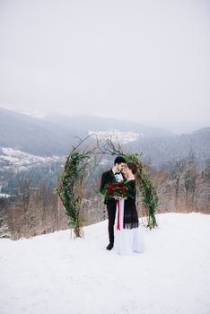 groom in a brown and bride in burgundy in the mountains Carpathians