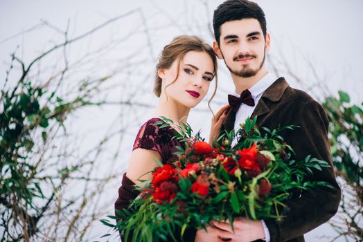 groom in a brown and bride in burgundy in the mountains Carpathians