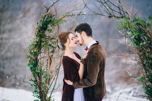 groom in a brown and bride in burgundy in the mountains Carpathians