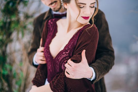 groom in a brown and bride in burgundy in the mountains Carpathians