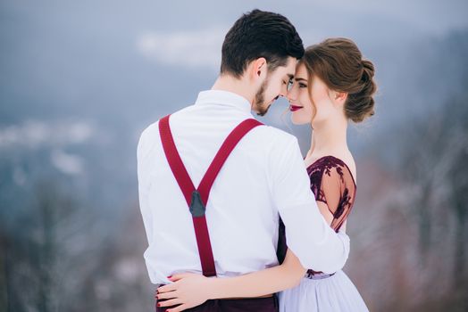 groom in a brown and bride in burgundy in the mountains Carpathians