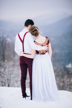 groom in a brown and bride in burgundy in the mountains Carpathians