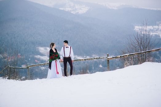 groom in a brown and bride in burgundy in the mountains Carpathians