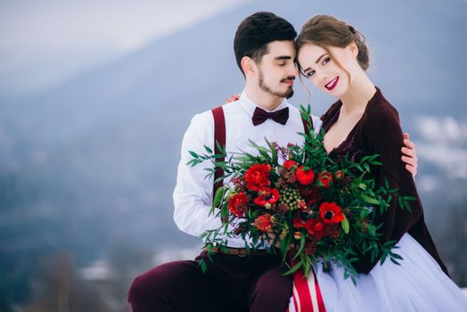 groom in a brown and bride in burgundy in the mountains Carpathians