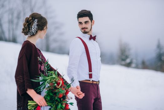 groom in a brown and bride in burgundy in the mountains Carpathians