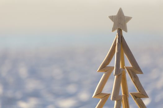 A driftwood Christmas tree closeup with the sand and surf out of focus behind