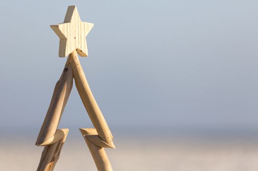 A wooden Christmas tree against a beach background with copy space.