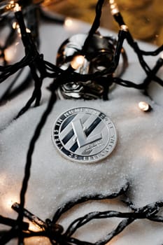 Digital currency physical metal silver litecoin coin. Christmas snow concept.