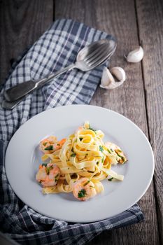 Tagliatelle with shrimps garlic on a wooden surface