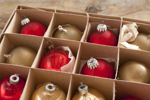 Cardboard box of colorful Christmas decorations with red and gold baubles or balls for the Xmas tree to celebrate the festive holiday season