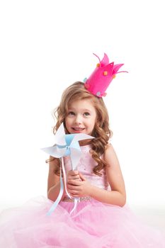 Beautiful little candy princess girl in crown holding pinwheel and smiling