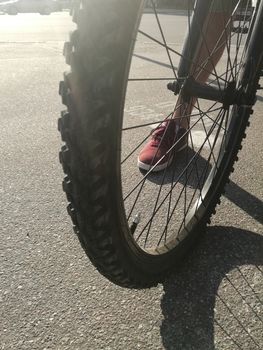 Wheel of a bicycle and male feet in sneakers close-up
