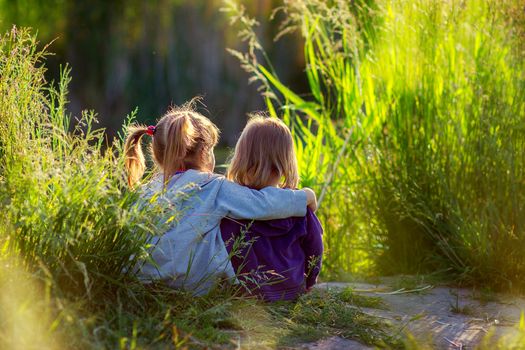 girls sit having embraced ashore at sunset