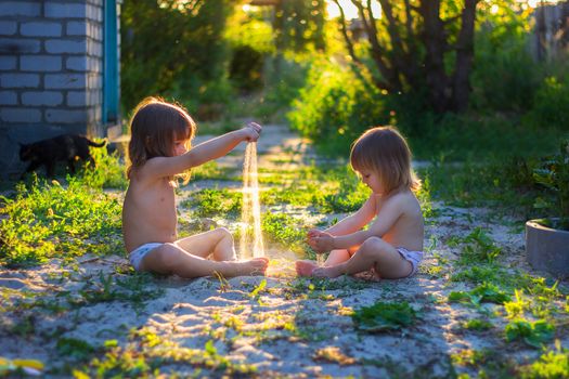 girls play with sand in the yard at sunset