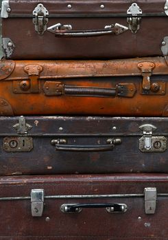 Stack of four old vintage antique grunge travel luggage brown leather suitcase trunks, close up, low angle front view