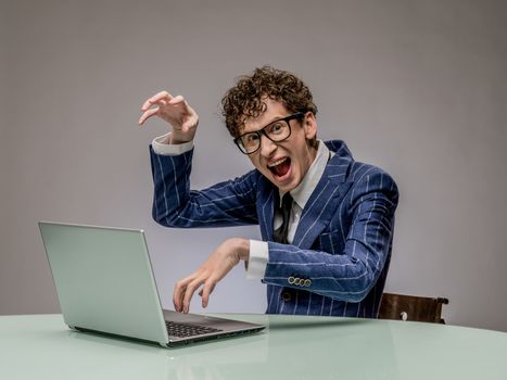 Funny business man geek using laptop with evil genius facial expression