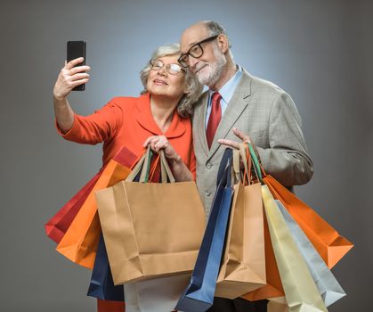 Happy couple taking selfie after shopping with many bags
