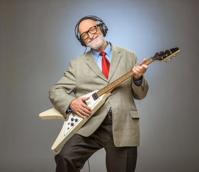 Happy funny senior man playing electric guitar