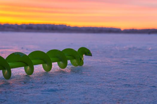 Fishing ice auger at dawn fishing drill ice beautiful sky