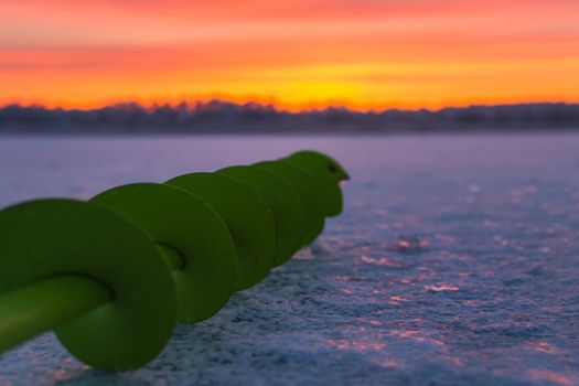 Fishing ice auger at dawn fishing drill ice beautiful sky