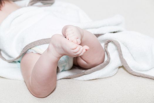 White towel around cute newborn feet. Close up picture of new born baby feet on a white sheet.