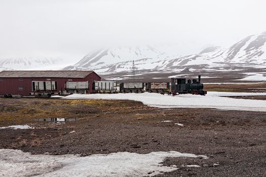 Old train and hut in a foggy day in Ny Alesund, Svalbard islands, Norway