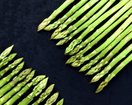 Borders of Fresh Asparagus Sprouts closeup on Black Slate background