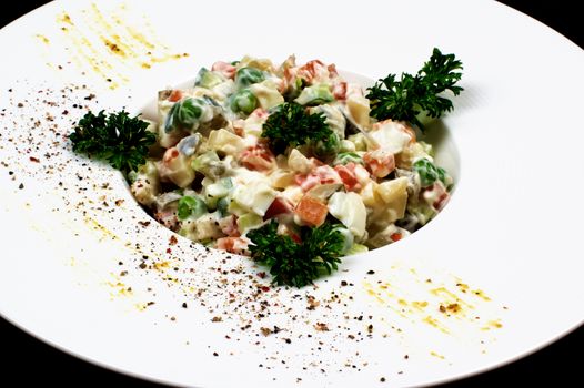 Traditional Russian Salad Olivier with Boiled Chicken Meat, Eggs and Vegetables Decorated with Parsley closeup in White Plate