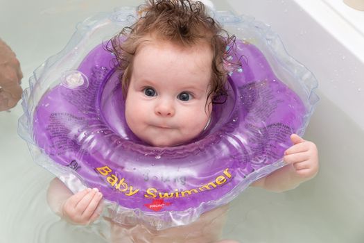 Baby swimming in bath with neck swim ring
