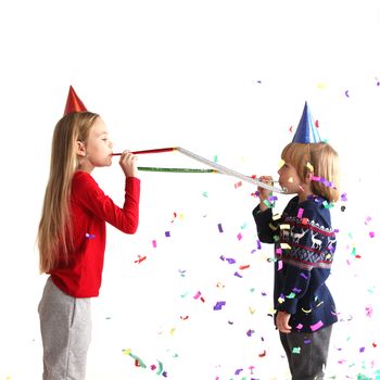 Children blowing party trumpets with confetti celebrating new year