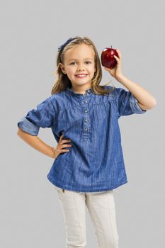 Studio portrait of a beautiful cute girl holding a fresh red apple