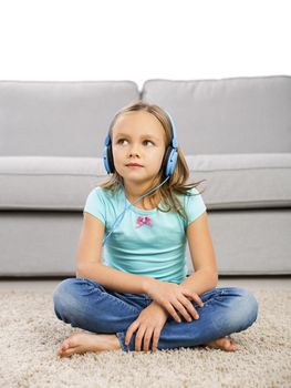 Little blonde girl at home listen music with headphones