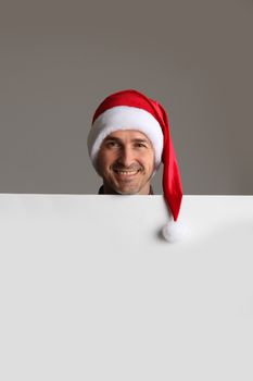 Happy man in Santa hat holding blank banner with copy space