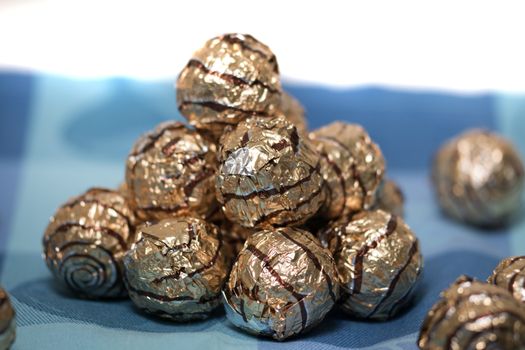 Pile of sweet round chocolate candies for christmas celebrations on a table cloth.