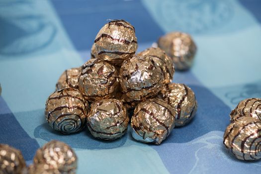 Pile of sweet round chocolate candies for christmas celebrations on a table cloth.