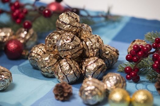 Pile of sweet round chocolate candies for christmas celebrations on a table cloth.