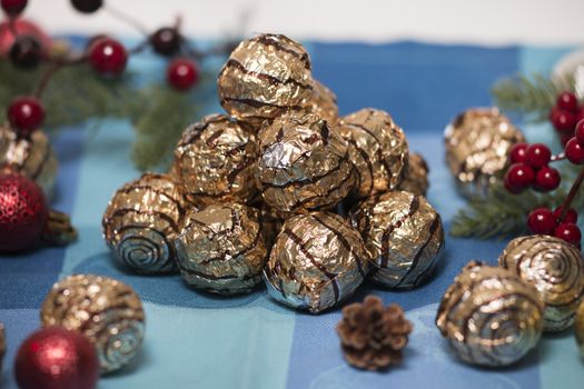 Pile of sweet round chocolate candies for christmas celebrations on a table cloth.