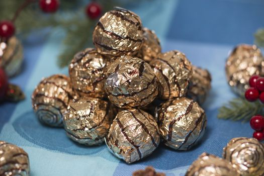 Pile of sweet round chocolate candies for christmas celebrations on a table cloth.