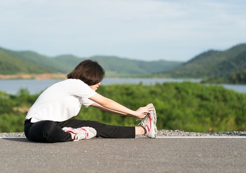 Fitness and lifestyle concept - Young asian woman short hair doing exercising outdoor and warm up preparing for jogging