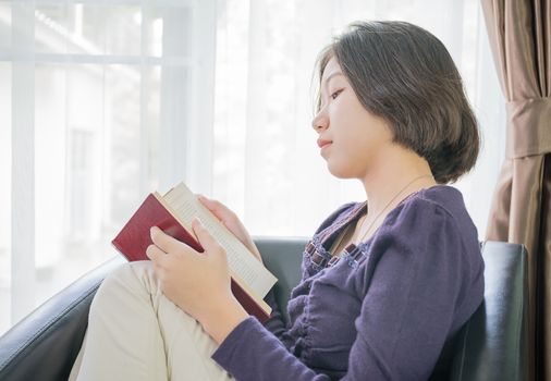Close up beautiful young asian woman short hair read a book in living room at home