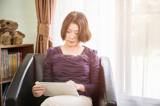 Close up beautiful young asian woman short hair use mobile phone in living room at home