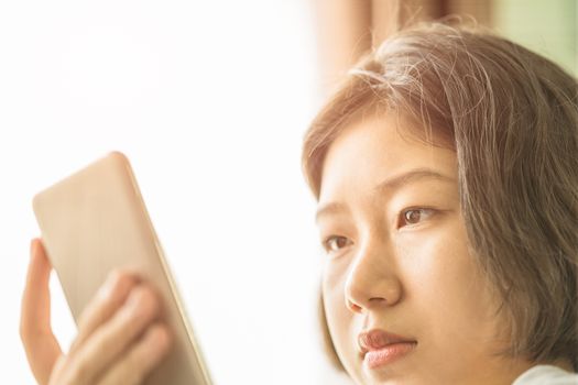 Close up young asian woman short hair listening music from mobile phone on the couch